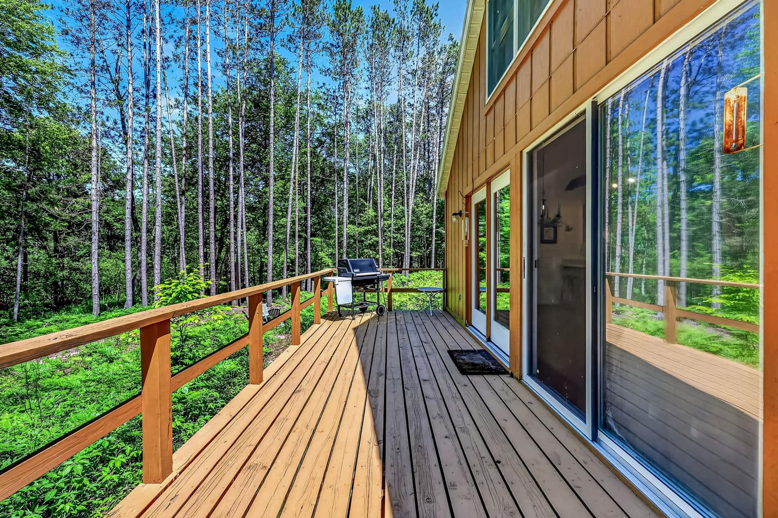 Cedar sided home with a wraparound deck set among tall pines on a wooded Newaygo County lot